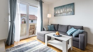 A modern living room with a grey sofa, a white coffee table, and a painting of sailboats on the wall. - VILLA TANGO I (Okrug Gornji)