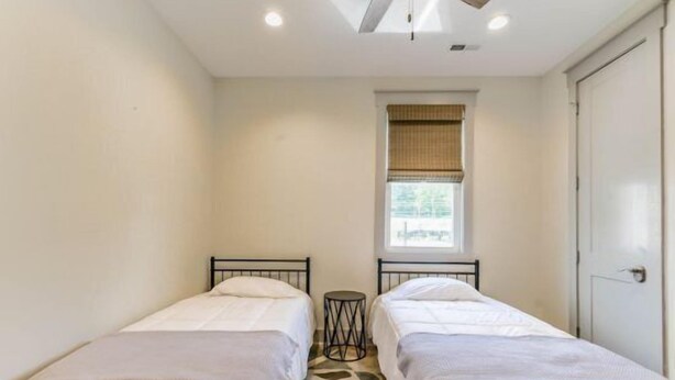 A small, clean room with two single beds, a window with blinds, and a door. - Enjoy Life at River Rocks Plantation (Guntersville)