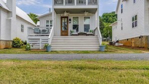 A two-story white house with a balcony, a front porch, and a small garden area. - Enjoy Life at River Rocks Plantation (Guntersville)