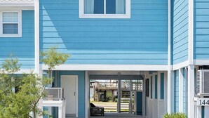 Un bâtiment à deux étages, avec une façade bleue, des ornements blancs et une entrée abritée dotée d’un banc.