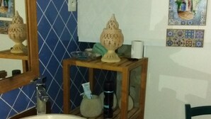 Une salle de bain avec un meuble-lavabo en bois, un lavabo blanc, un miroir et une chaise.