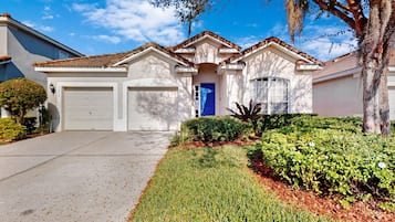 A residential house with a garage, a blue door, and a well-maintained lawn.