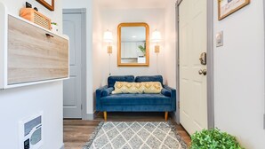 A hallway with a blue sofa, a patterned rug, a mirror, and a door. - French Toast Flat (Moscow)
