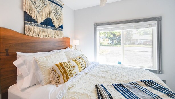 A bedroom with a wooden headboard, a large window, and a ceiling fan. - French Toast Flat (Moscow)