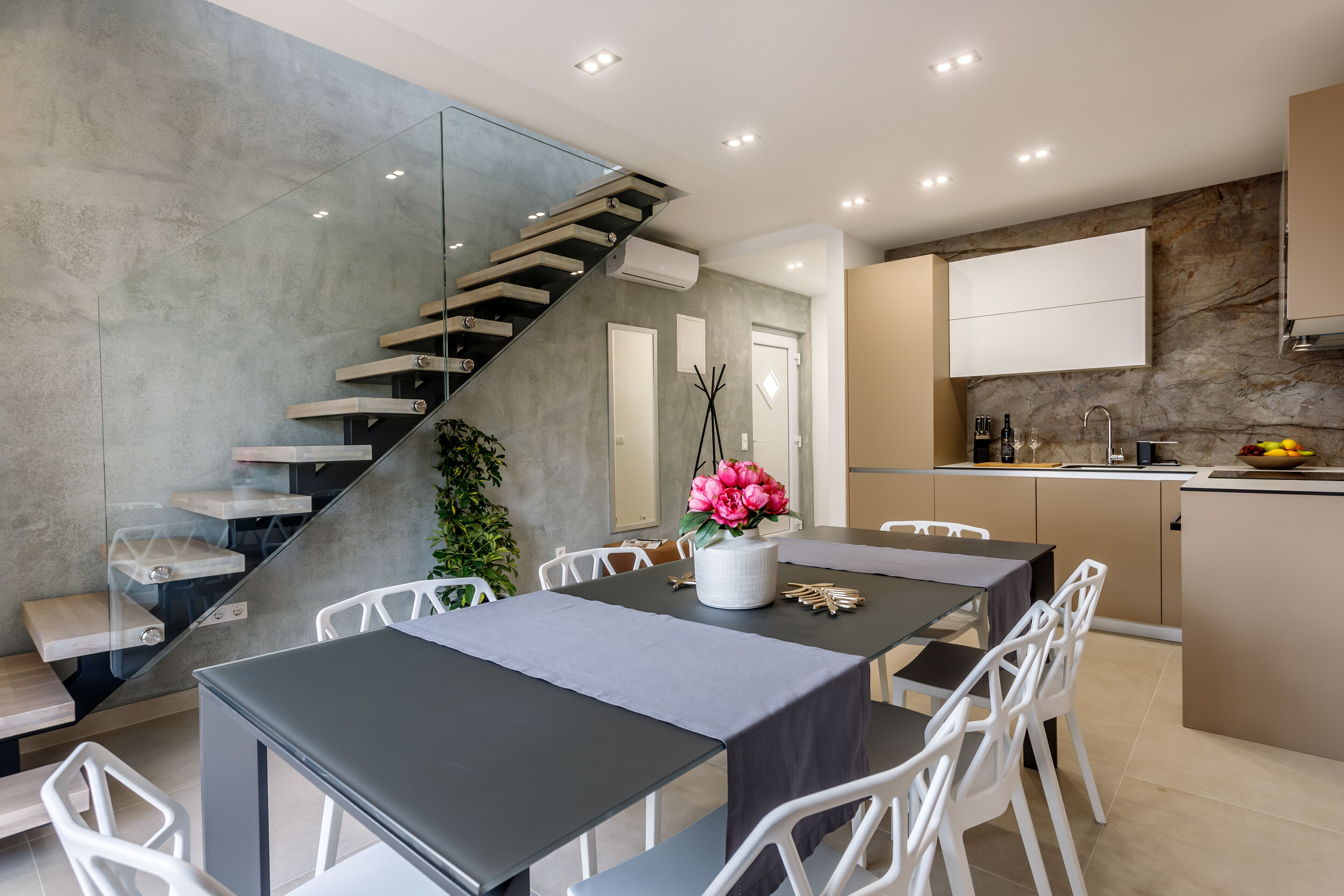 A modern kitchen with a built-in stove, white cabinets, and a dining area with a table and chairs.