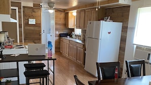 Une cuisine dotée de meubles en bois, d’un réfrigérateur, d’une cuisinière et d’un coin repas avec une table et des chaises.