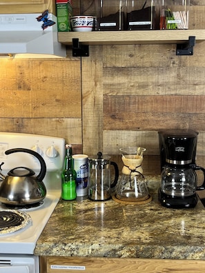 A kitchen counter with a kettle, coffee maker, and various containers. - Home in the heart of West Virginia adventure country! (Mount Hope)