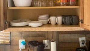 Un meuble de cuisine doté d’étagères où sont rangés divers ustensiles de cuisine, notamment des assiettes, des bols, des verres et des tasses.