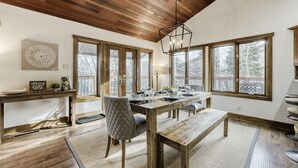 A dining area with a wooden table, chairs, and a hanging light fixture.