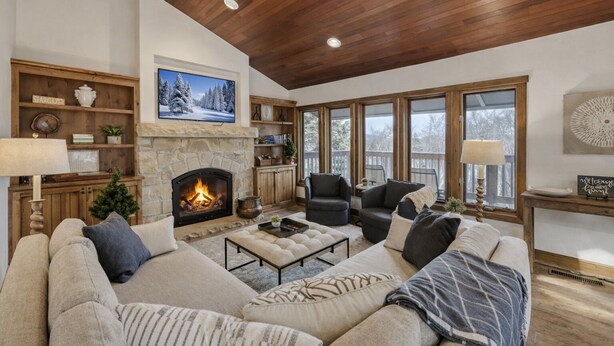A cozy living room with a fireplace, comfortable seating, and large windows.