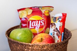 Ein Korb mit Lay's Kartoffelchips, einer Schokoladenriegel und zwei Äpfeln.