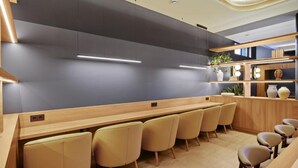 Ein modernes Interieur mit einer langen Holztresen, mehreren Stühlen und eingebauten Regalen mit dekorativen Gegenständen.