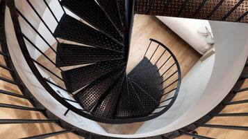 Una escalera de caracol con barandilla negra y peldaños blancos.