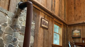 Un intérieur rustique avec un mur en pierre, un plafond en bois, une grande horloge et un poêle.