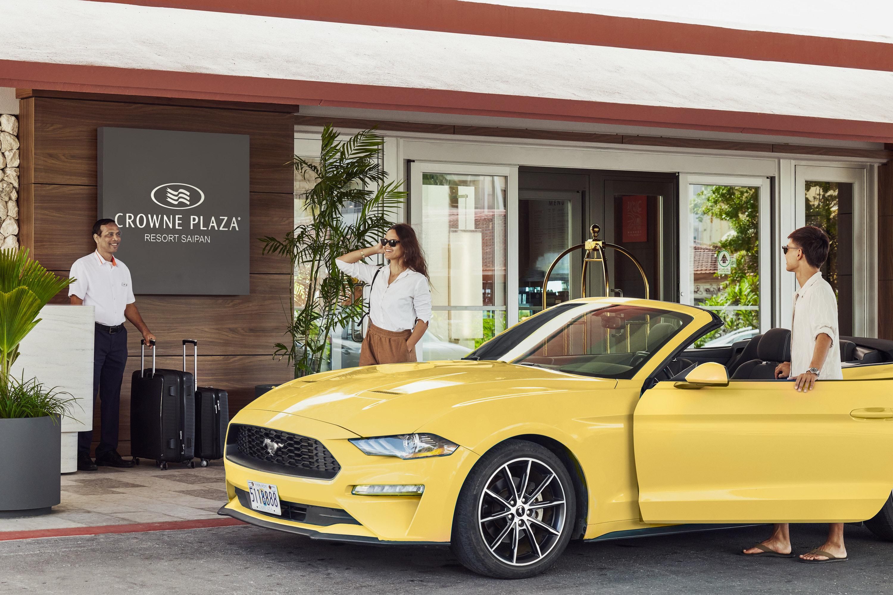 A yellow convertible car parked in front of Crowne Plaza Resort Saipan.