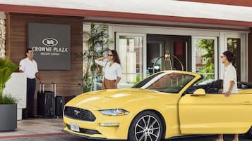 A yellow convertible car parked in front of Crowne Plaza Resort Saipan.