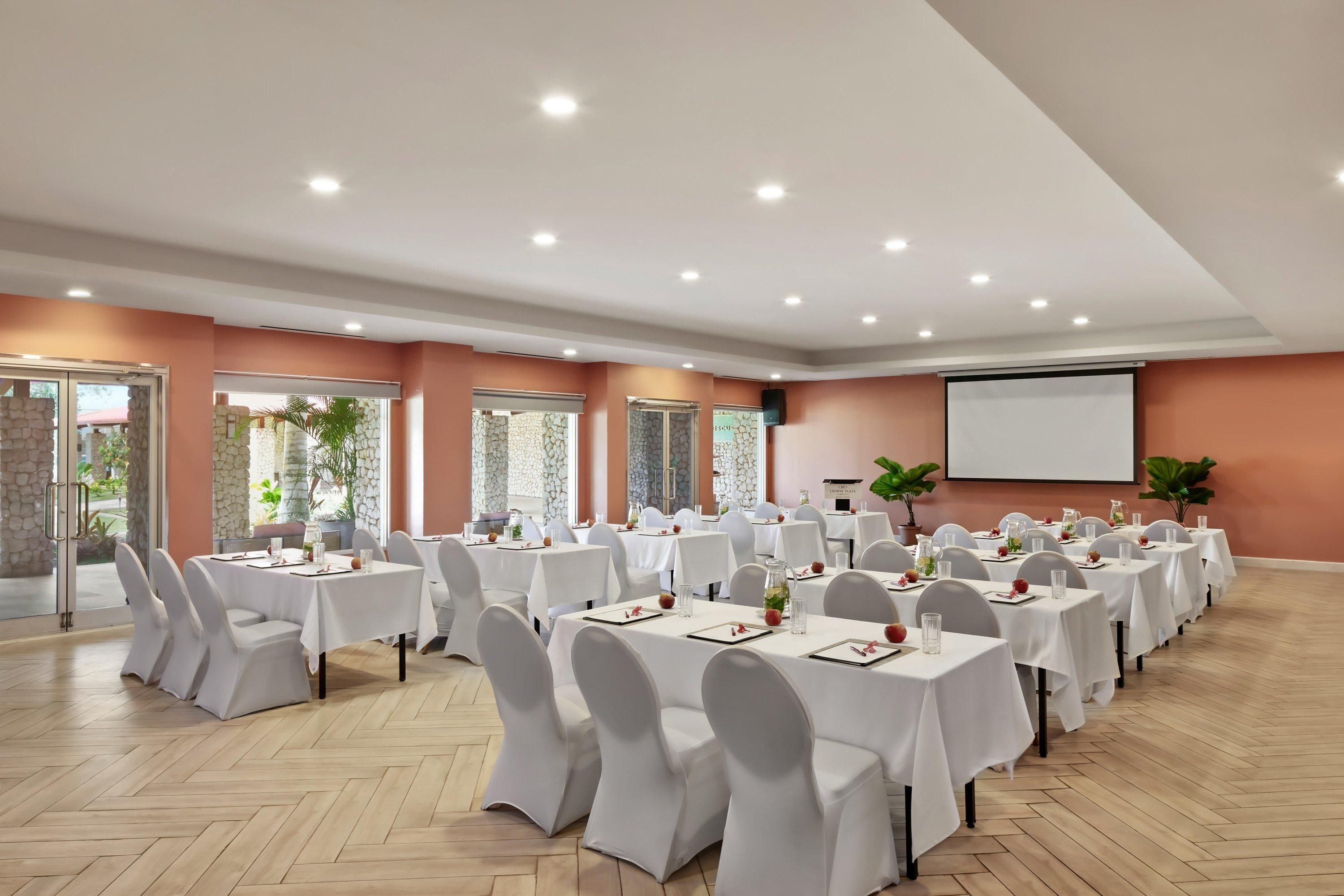 A conference room with multiple tables, chairs, and a projector screen.