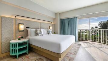 A hotel room with a large bed, a small side table, a nightstand, a large window with a view, and a balcony.