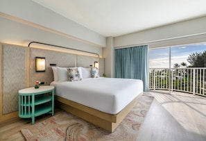 A hotel room with a large bed, a small side table, a nightstand, a large window with a view, and a balcony. - Crowne Plaza Saipan (Saipan)