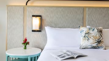 A hotel room with a bed, a bedside table, a lamp, and a magazine.