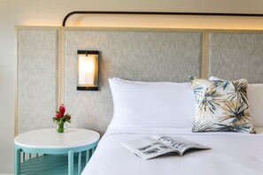 Una habitación de hotel con una cama, una mesita de noche, una lámpara y una revista.