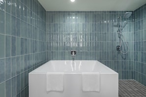 A modern bathroom with a large bathtub, a showerhead, and a faucet.