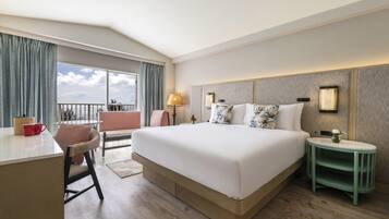 A hotel room with a large bed, a desk, a chair, a nightstand, and a view of the outdoors.