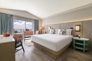 Une chambre d’hôtel avec un grand lit, un bureau, une chaise, une table de chevet et une vue sur l’extérieur.