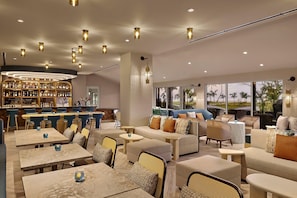 A modern lounge area with seating, tables, and a bar.