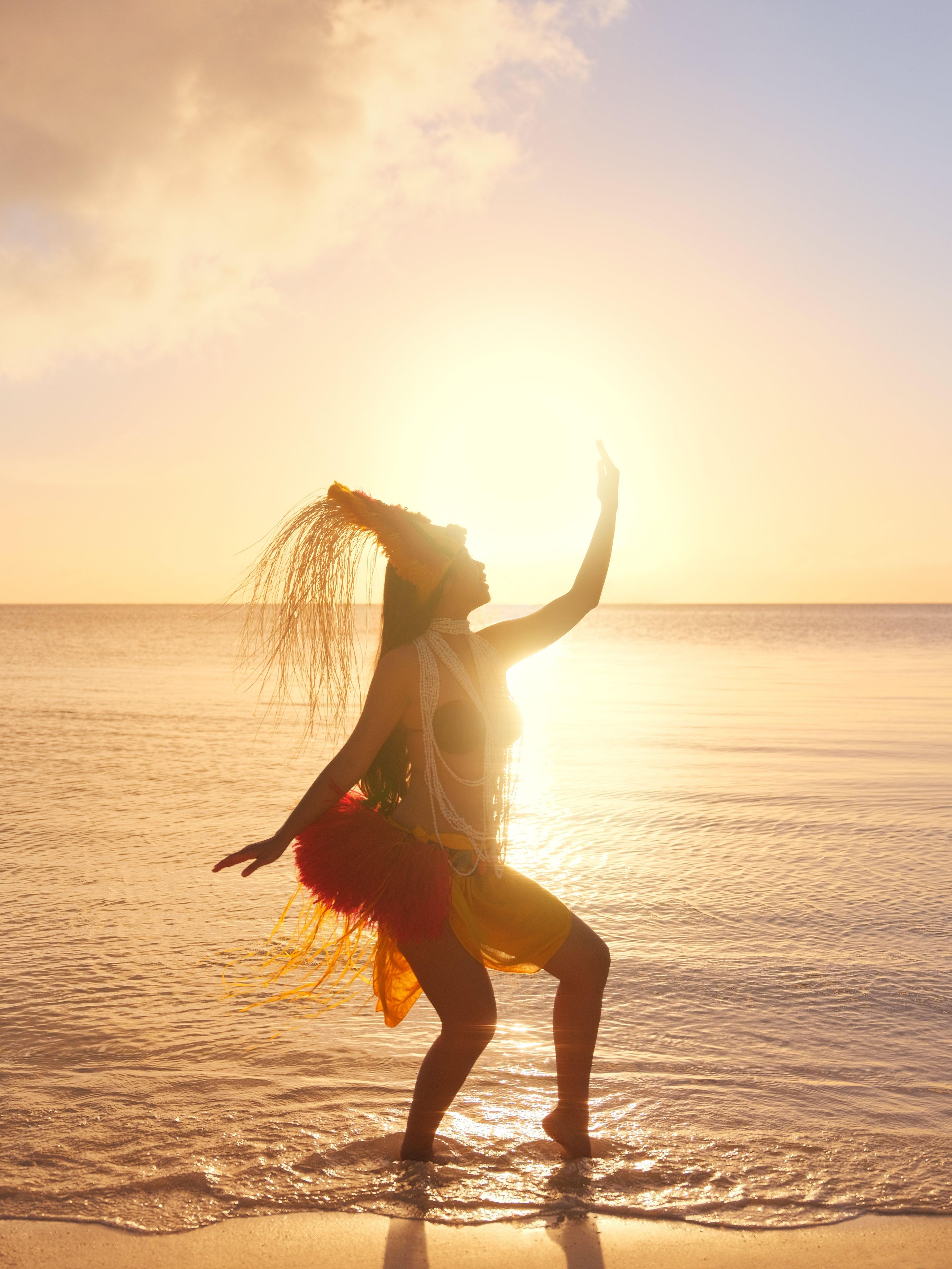 A person performing on a beach with the ocean and a sunset in the background.