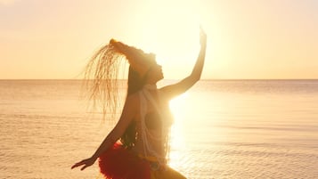 A person performing on a beach with the ocean and a sunset in the background.