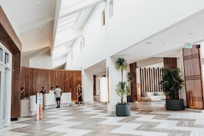 A spacious lobby with a reception desk, a seating area with a sofa, and potted plants. - Crowne Plaza Saipan (Saipan)