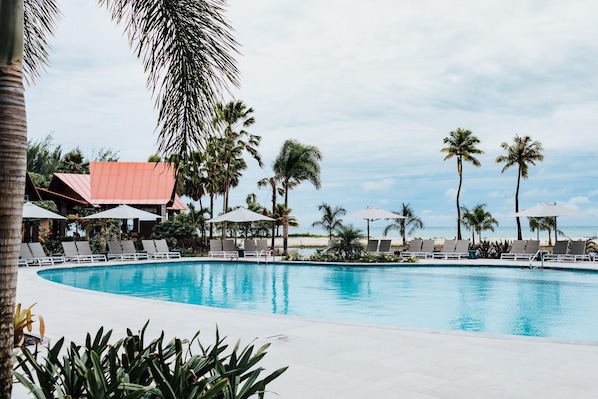 A pool area with lounge chairs, umbrellas, and palm trees. - Crowne Plaza Saipan (Saipan)