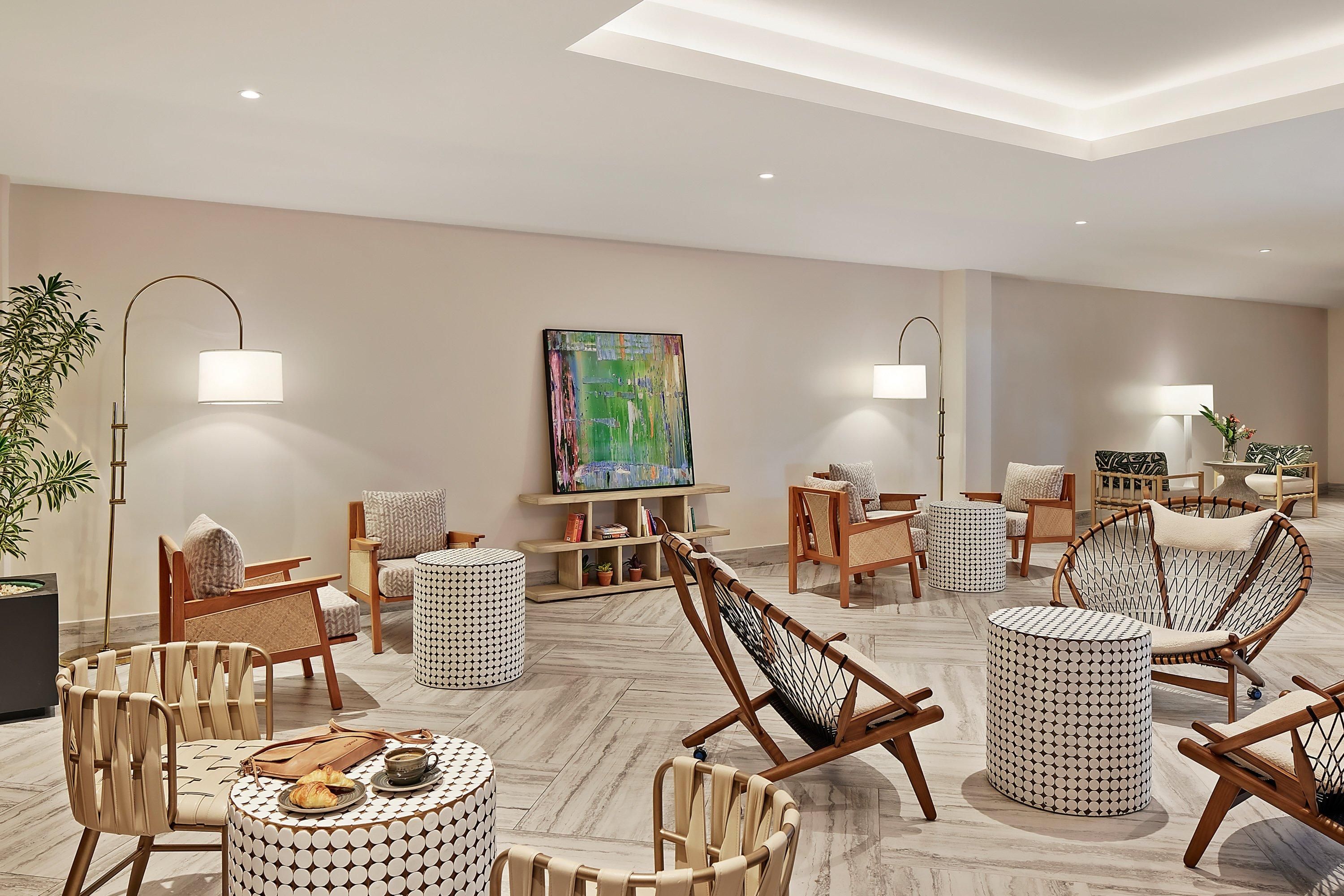 Un salon moderne avec un canapé, des fauteuils, une table basse et un tableau accroché au mur.