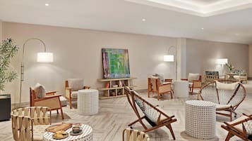 Un salon moderne avec un canapé, des fauteuils, une table basse et un tableau accroché au mur.
