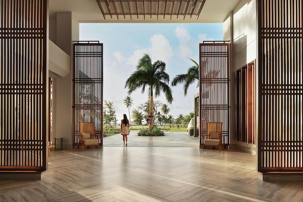 A spacious lobby with a modern design, featuring a large palm tree and a view of the outdoors.