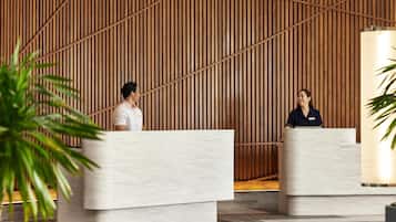 A reception area with two marble reception desks, wooden slat wall, and potted plants.
