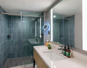 A modern bathroom with a glass-enclosed shower, a large mirror, and a countertop with a sink and toiletries. - Crowne Plaza Saipan (Saipan)