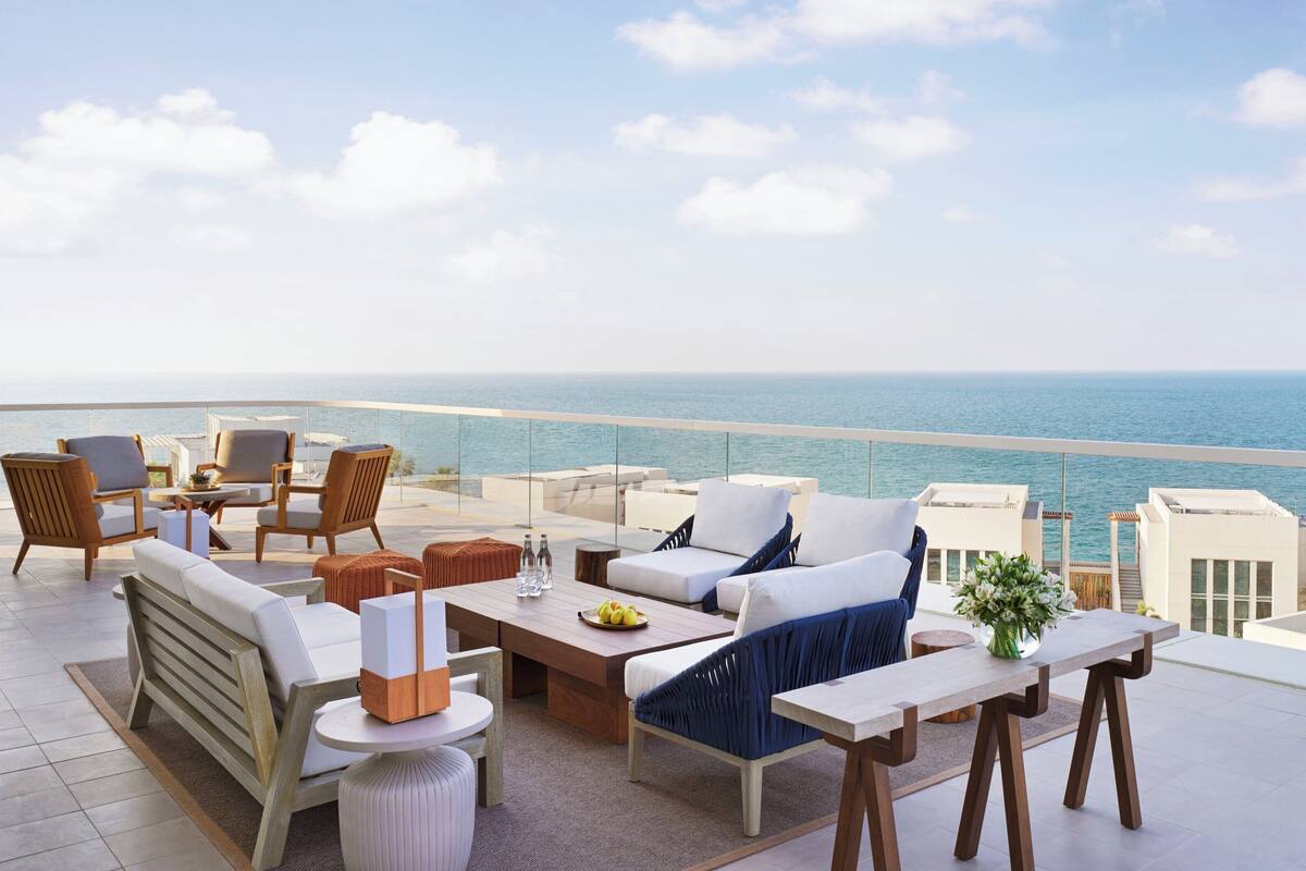A spacious outdoor terrace with a view of the sea, furnished with sofas, chairs, and a dining table.