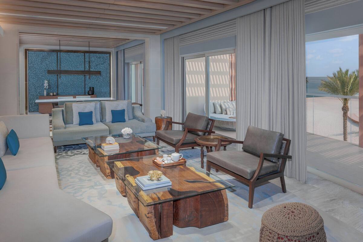A modern living room with a sofa, chairs, a coffee table, and a view of the ocean.