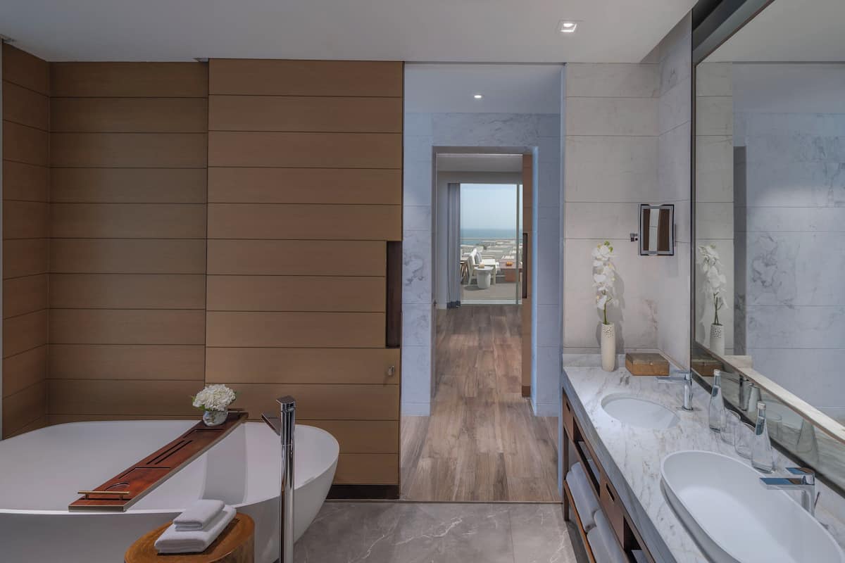 Un baño moderno con una bañera grande, dos lavamanos y un espejo.