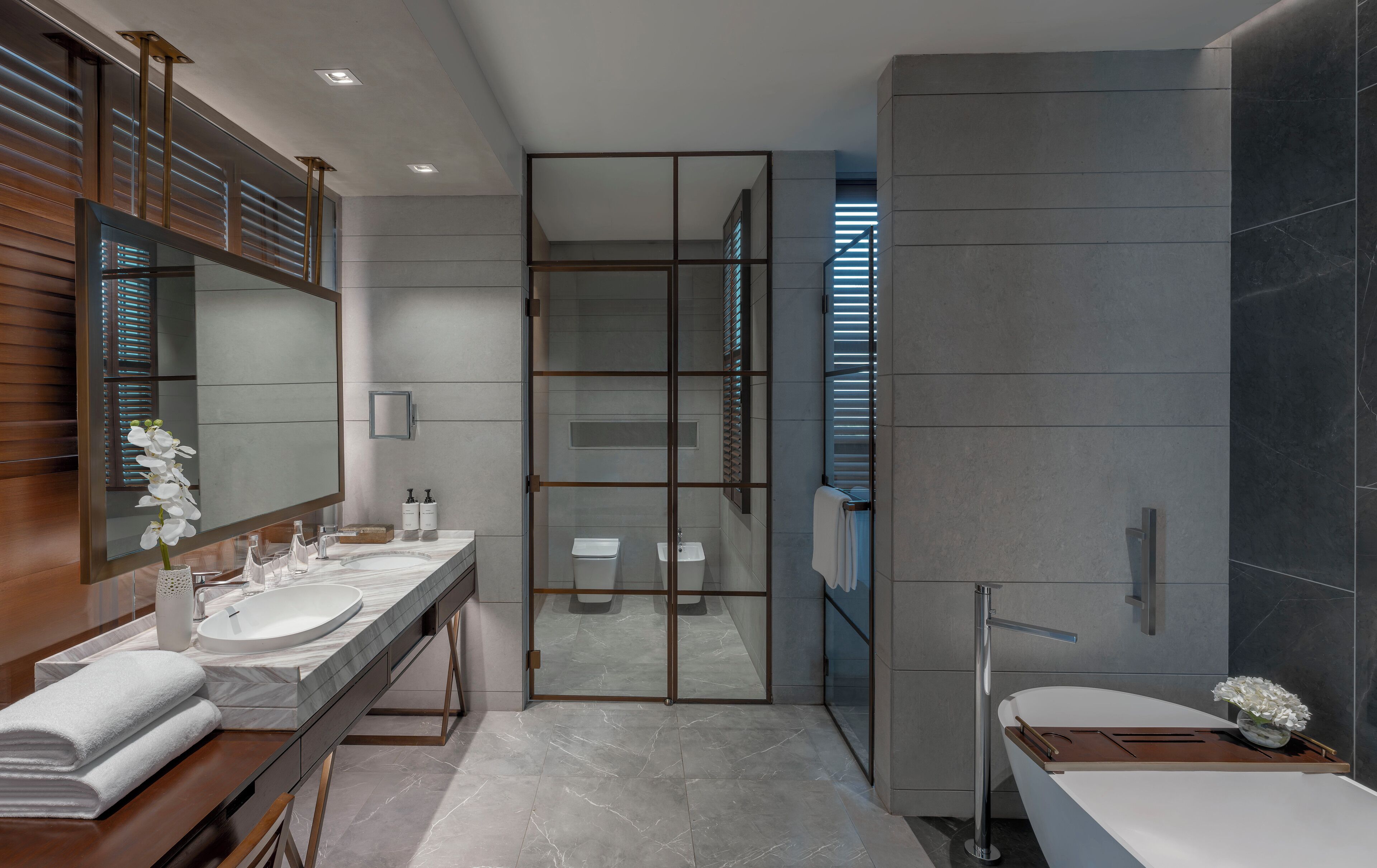 Une salle de bain moderne dotée de deux lavabos, d’un grand miroir et d’une douche à l’italienne.
