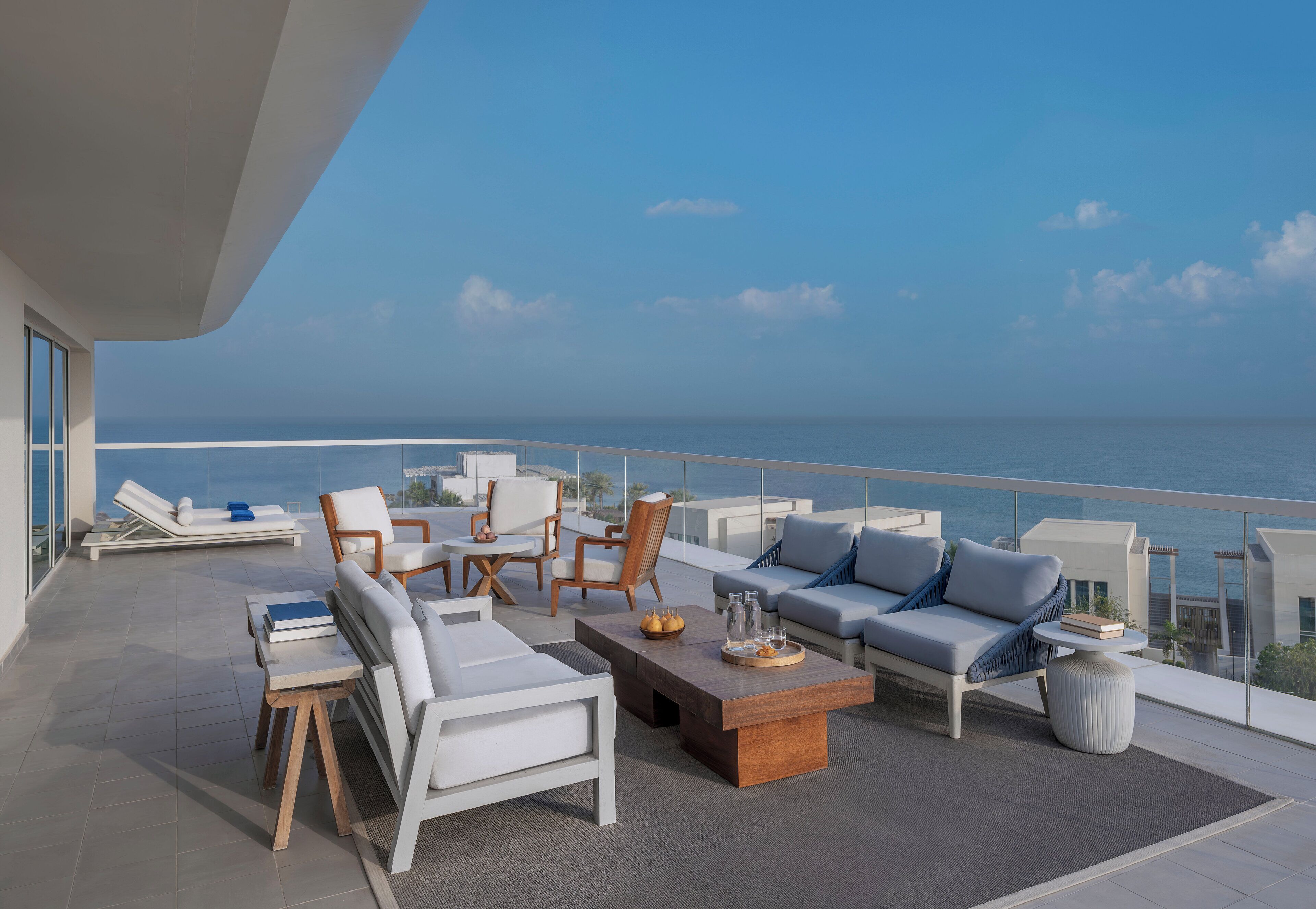 A modern outdoor lounge area with seating and a view of the ocean.