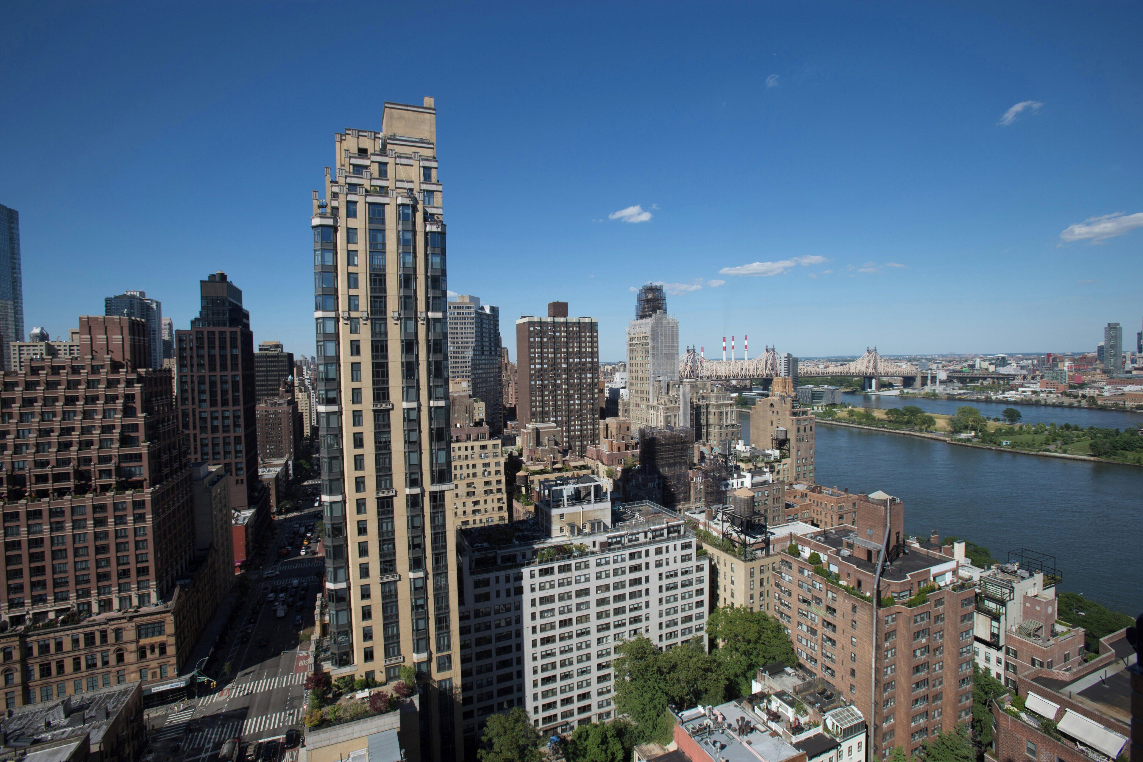 A cityscape with high-rise buildings, a river, and a clear sky.