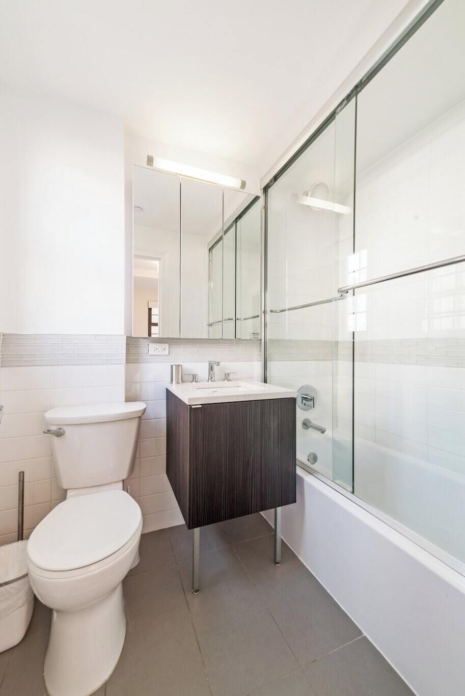A modern bathroom with a toilet, sink, and glass shower enclosure.