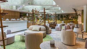 Ein stilvoller Lounge-Bereich mit runden Sitzgelegenheiten, einer Bar und diversen Pflanzen.