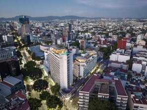 Une vue urbaine mettant en valeur un bâtiment remarquable, doté d’un jardin sur le toit et d’un design moderne.