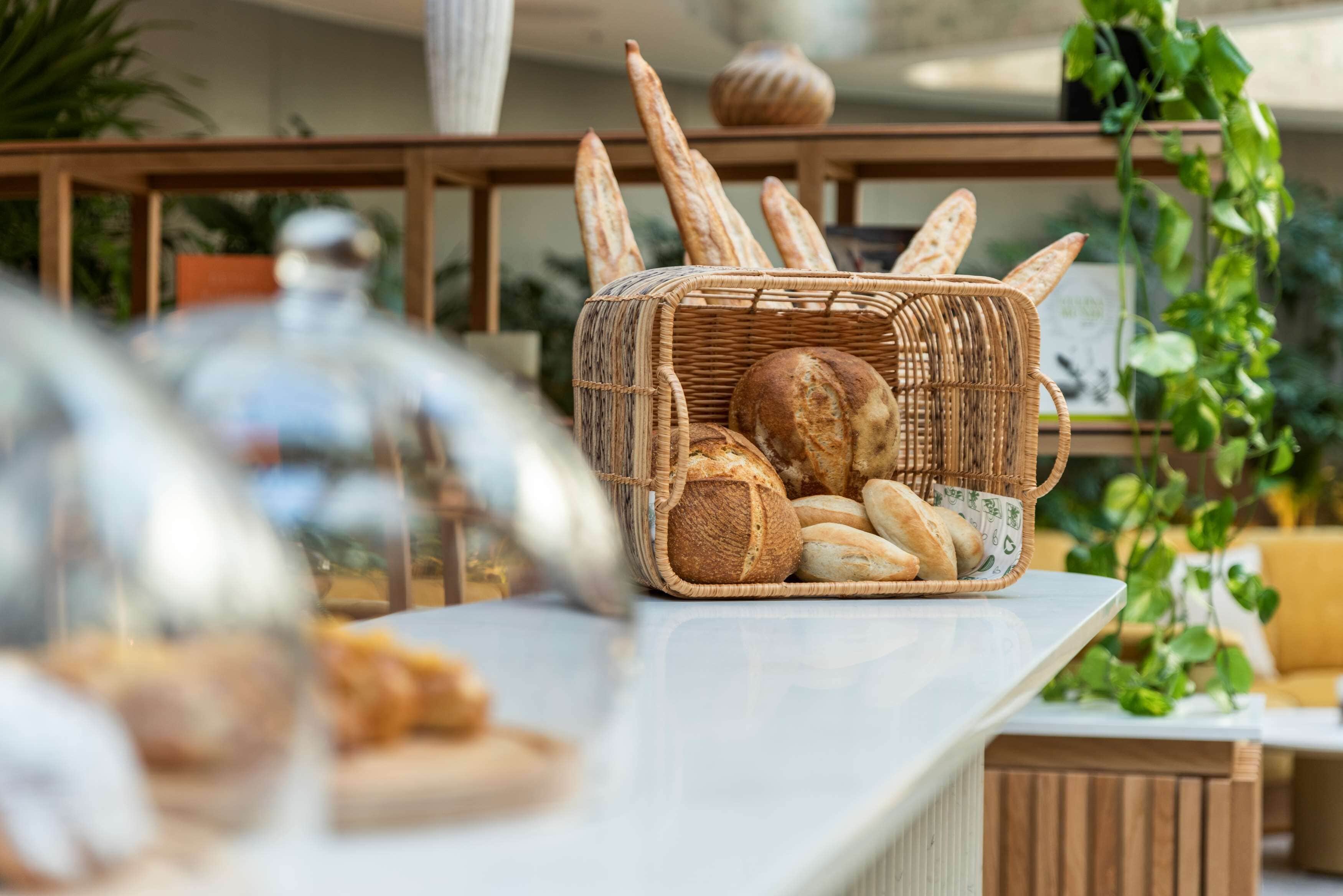Ein Korbwicker-Korb mit verschiedenen Brotsorten auf einer Arbeitsplatte.