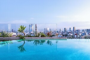 Una piscina azul cristalina con el horizonte de una ciudad al fondo.