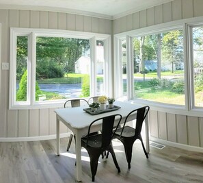 Enjoy meals in this dining area with a table and two chairs, surrounded by paneled walls and large windows offering a view of the surrounding landscape.